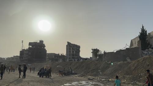 Palestinians walk amid destroyed buildings in Gaza.